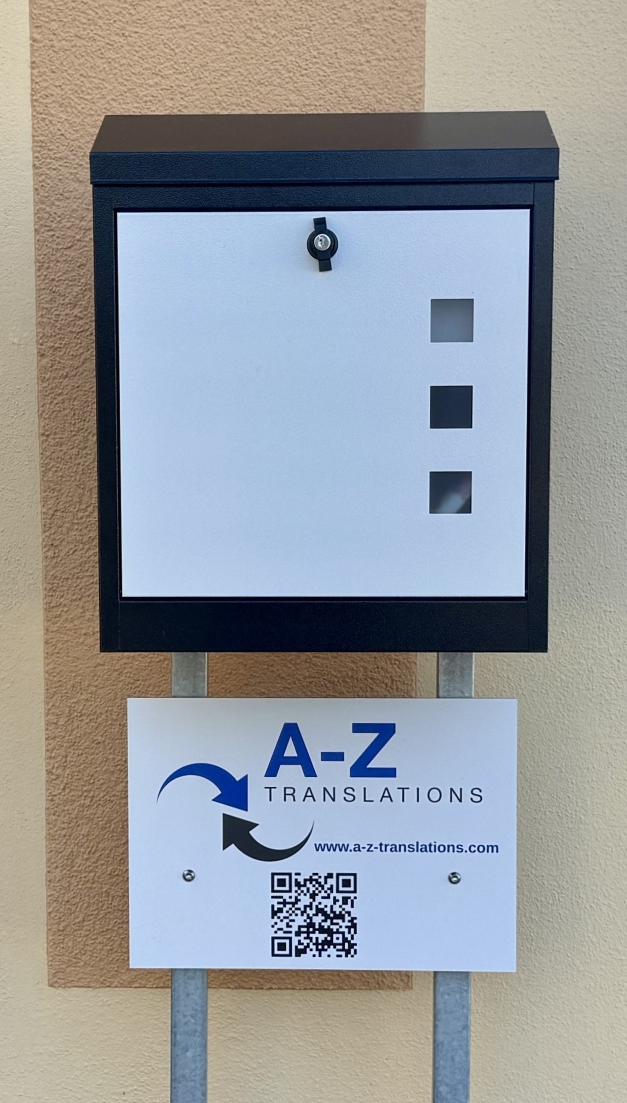 mail box in gray and white with business sign underneath with A-Z Translations logo and QR code