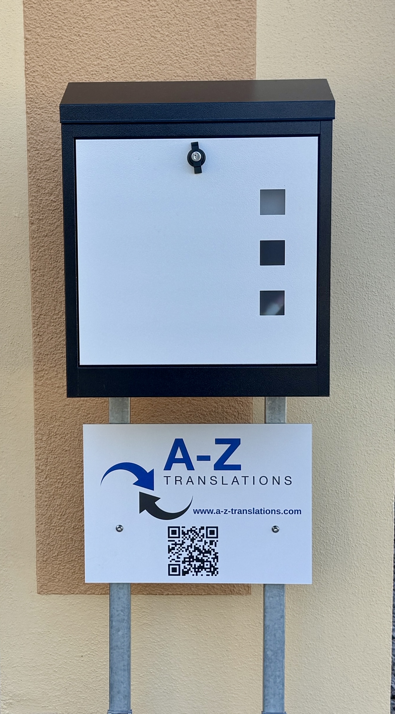 mail box in gray and white with business sign underneath including A-Z Translations logo and QR code